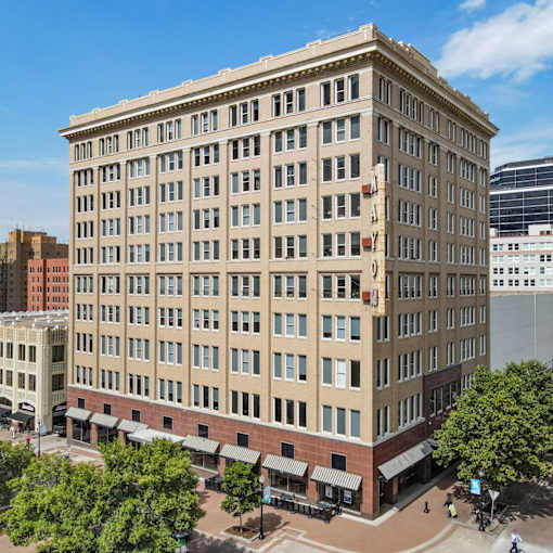 A large beige building with a red brick base and a black awning.