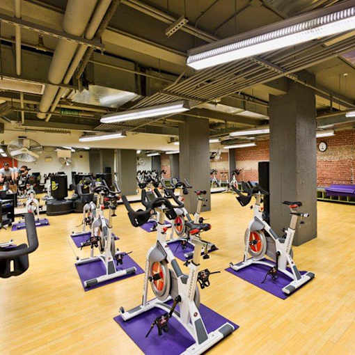 A gym with exercise bikes and a brick wall.
