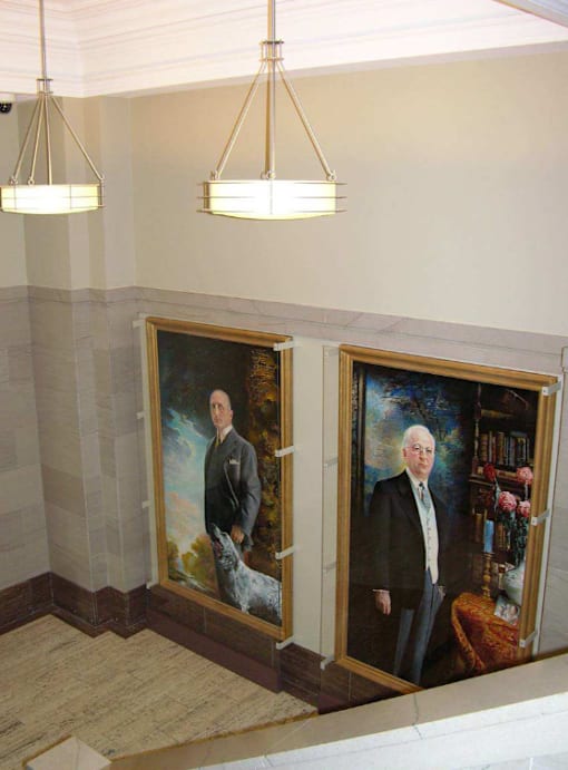 Two portraits of men are hanging in a hallway.
