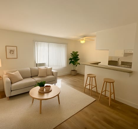 A living room with a white couch, a wooden coffee table, and a bar area with stools.