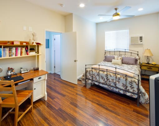 Apartment bedroom with ceiling fan and wood flooring