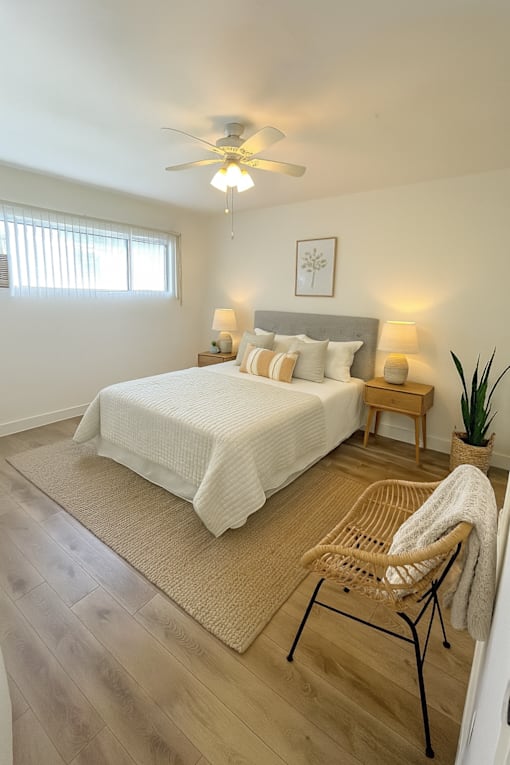 A bedroom with a bed, chair, and ceiling fan.