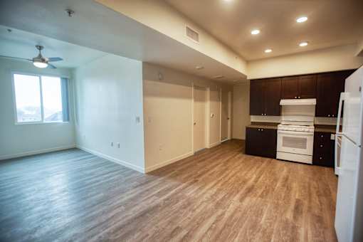 an empty kitchen and living room with wood floors and white appliances