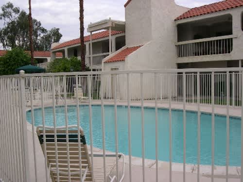 A pool surrounded by a white fence with a chair on it.