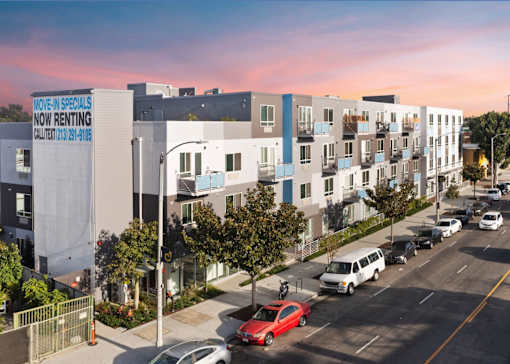 A street view of a residential area with a sign that says "MOVIE SPECIALS NOW RENTING".