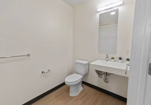 A white toilet sits in a small bathroom with a white sink and a white bathtub.