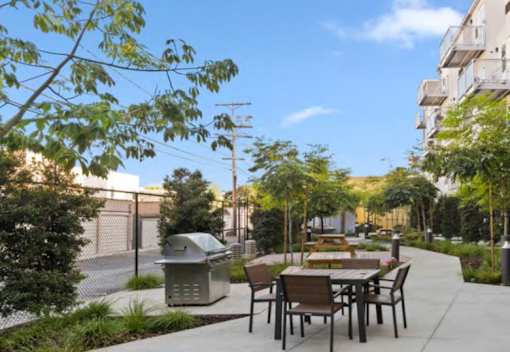 A patio with a table and chairs is surrounded by trees and bushes.