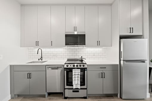 A modern kitchen with a stove, sink, and refrigerator.