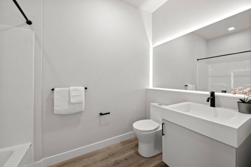 A white bathroom with a toilet, sink, and mirror.