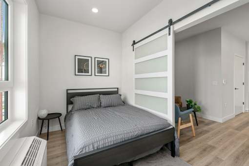 A bedroom with a large bed and a chair.