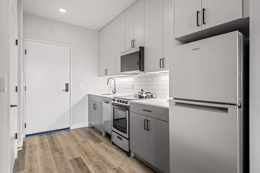 A modern kitchen with stainless steel appliances and wooden floors.