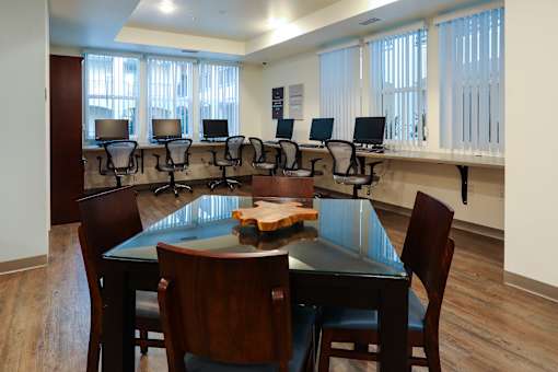 a conference room with a table and chairs and a row of computers