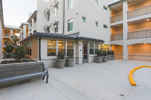 the entrance to a courtyard with a bench and an apartment building