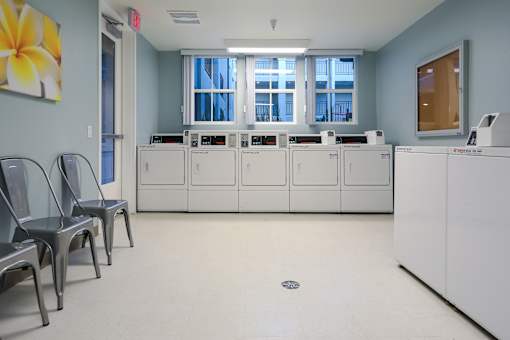 an empty room with white washers and dryers and chairs