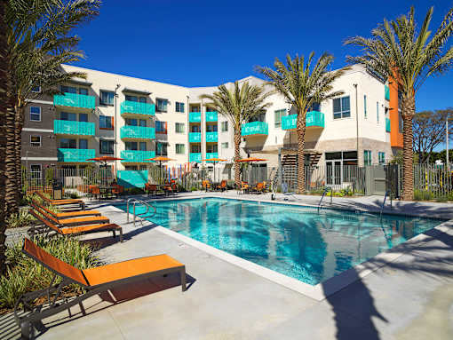 A pool area with sun loungers and a building in the background.