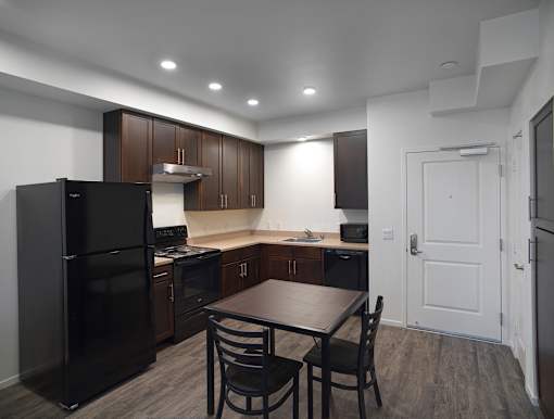 A kitchen with a black refrigerator and brown cabinets.