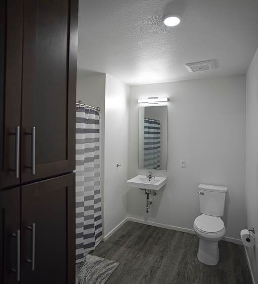 A white toilet sits in a bathroom with a white sink and a mirror.