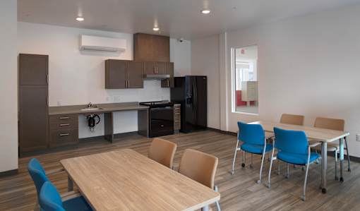 A conference room with a table, chairs, and a kitchen area in the background.