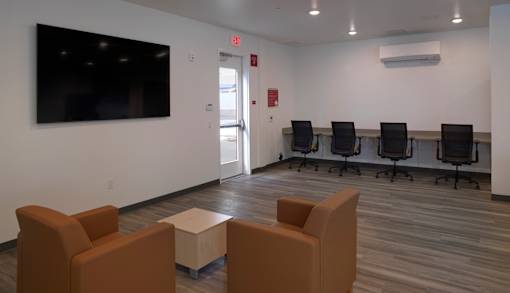 A conference room with a large screen, chairs, and a table.