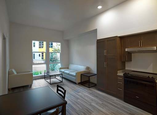 A modern kitchen with dark wood floors and white appliances.