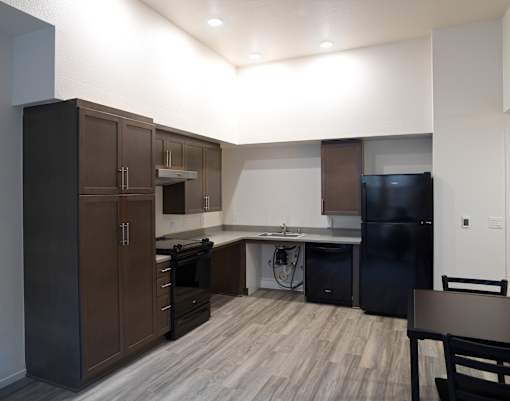 A kitchen with dark wood cabinets and a black fridge.
