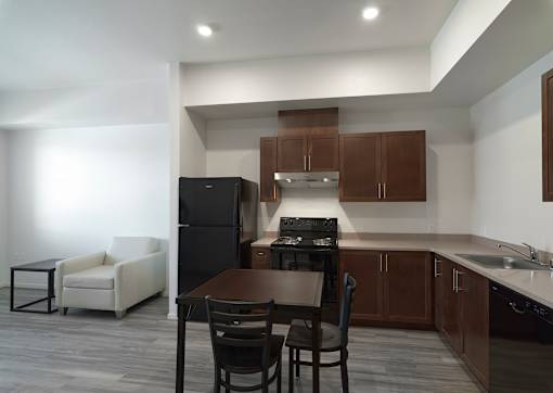 A modern kitchen with dark brown cabinets and a black refrigerator.