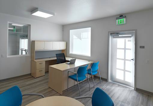 A conference room with a desk, chairs, and a laptop.
