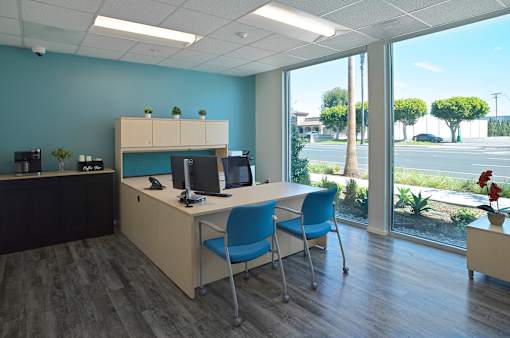 A room with a desk, chairs, and a computer.