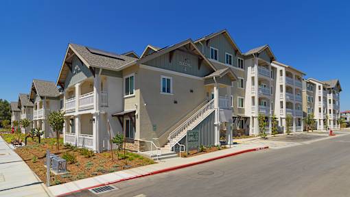 Apartment complex with multiple buildings and a clear blue sky.