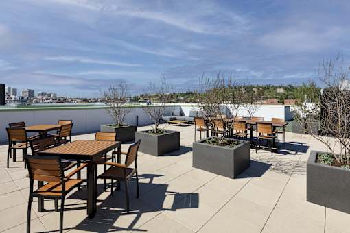 A patio with tables and chairs overlooking a body of water.