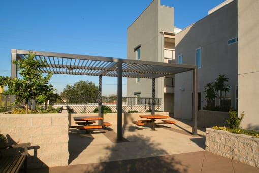 a patio with benches and awning in front of a building