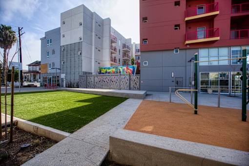 a courtyard between two buildings with grass and a playground