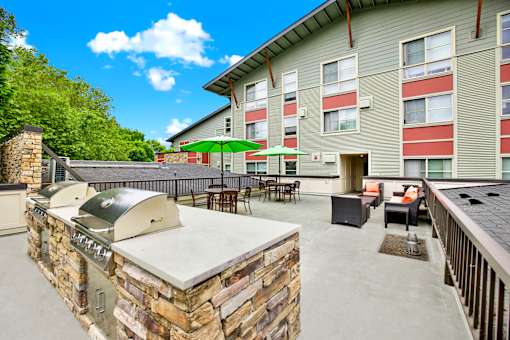 A patio with a stone barbecue and chairs.