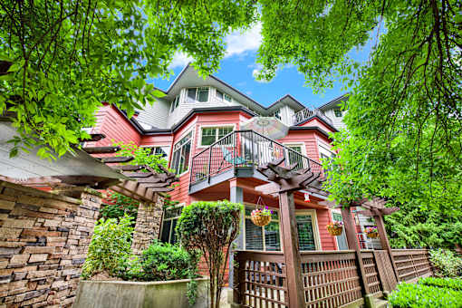 A house with a red and white exterior is surrounded by trees and greenery.