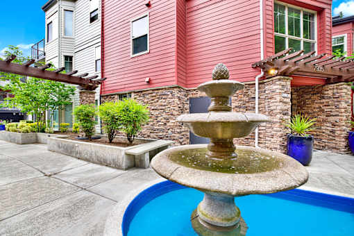 A fountain in the middle of a pool surrounded by a house.