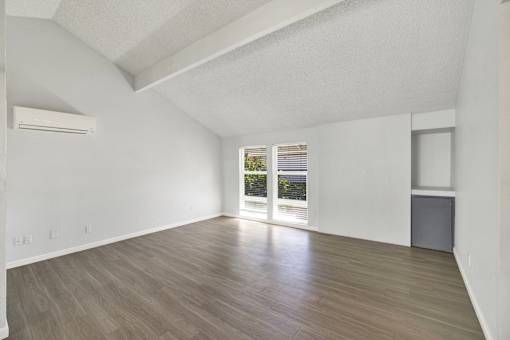 A spacious room with wooden flooring and a large window.