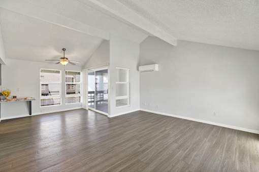 A room with a ceiling fan and sliding glass doors.