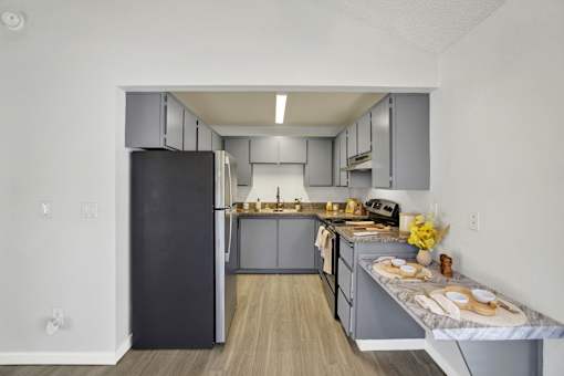 A kitchen with a black refrigerator and wooden floors.