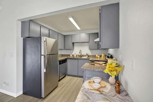 A modern kitchen with a stainless steel refrigerator and a table set for two.