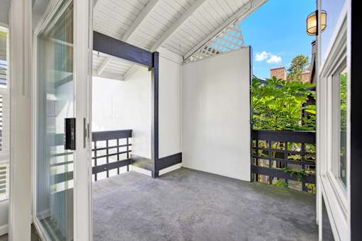 A patio with a white door and a black railing.