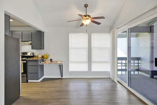 A kitchen with a ceiling fan and a dining table with chairs.