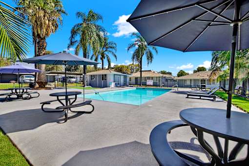 Pool deck with shade umbrellas and seating at Coventry Square Apartments, Upland