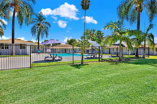 Fenced pool area with surrounding green lawn at Coventry Square Apartments, Upland, CA 97186