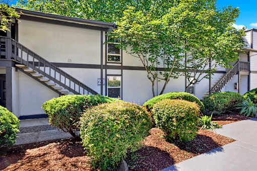 A building with a staircase and a tree in front.