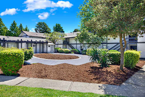A building with a landscaped front yard and a tree.