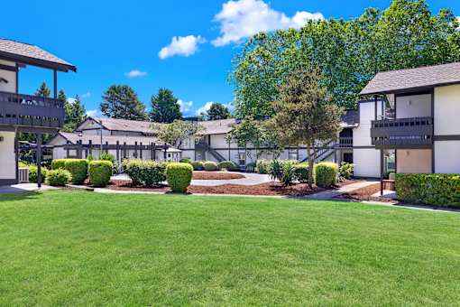A sunny day at a residential complex with green lawns and trees.