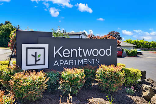 A sign for Kentwood Apartments is surrounded by shrubbery.