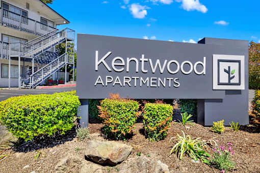 A sign for Kentwood Apartments is displayed in front of a building.