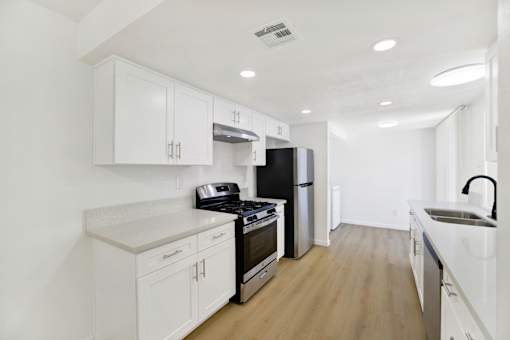 Galley kitchen with white cabinetry and gas range at Coventry Square Apartments, Upland, CA 97186