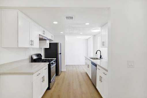 Galley kitchen with white cabinetry and recessed lighting at Coventry Square Apartments, Upland, CA